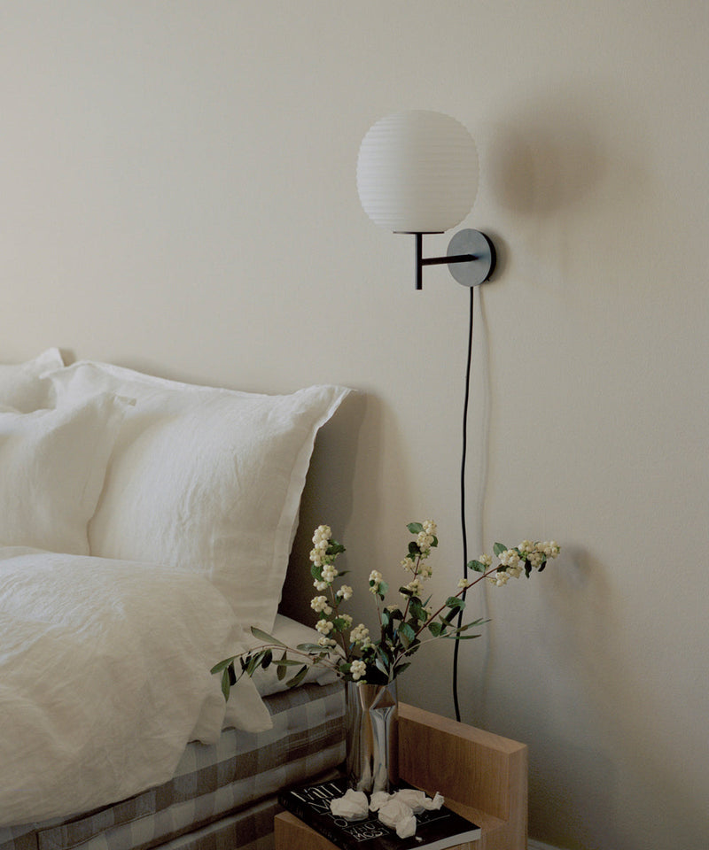 New Works Lantern Wall Light next to a bed