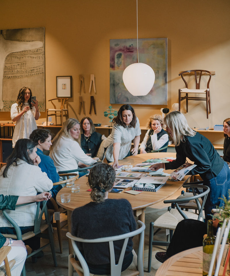 A group gathered around a table with two people giving instructions about the colour workshop they are about to undertake 