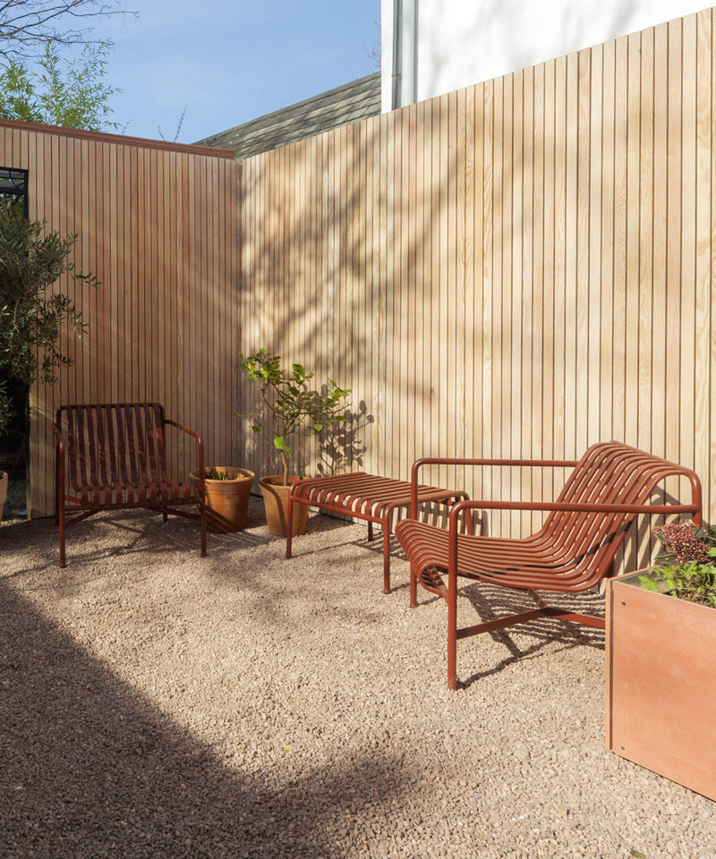 Two Palissade Lounge Chairs with a matching ottoman in a small courtyard garden
