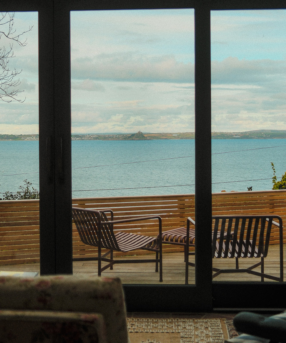 A view through glass door looking out onto the balcony with the sea in the distance