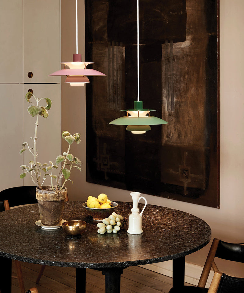 Two PH5 Mini pendants hanging above a wooden dining table