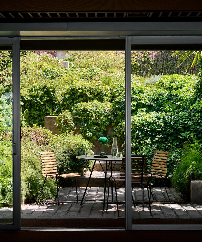 A small city garden with plants and a small patio with garden furniture on
