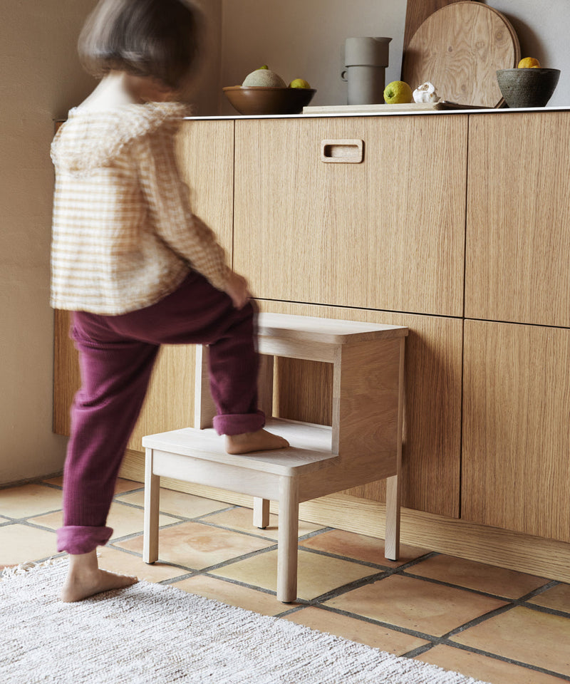 Child using the Form & Refine A Line Step Stool to reach something off the kitchen counter