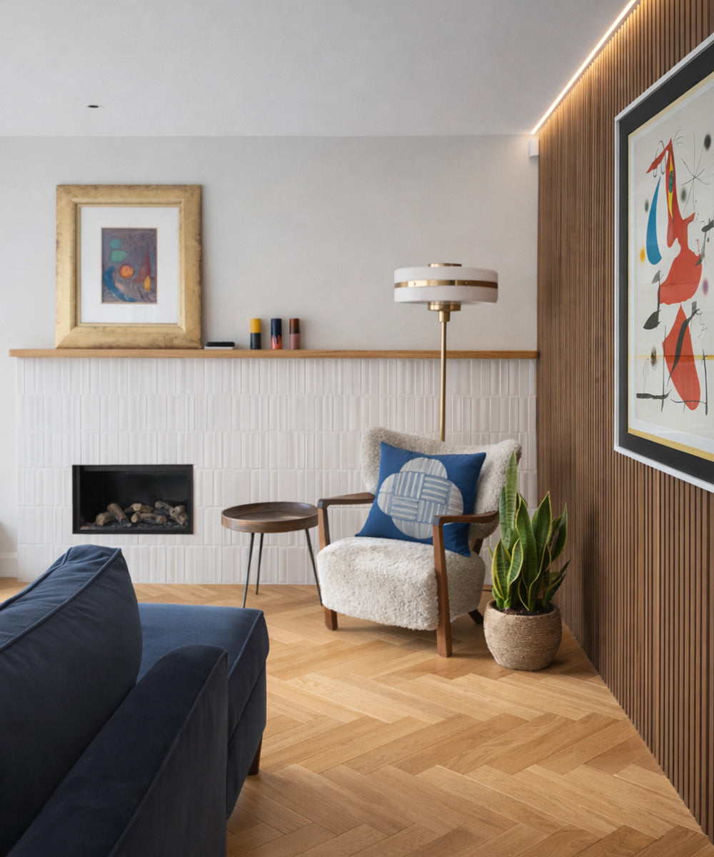 A image of a corner of a bright living room featuring a sheepskin lounge chair styled with a plant and a large floor lamp behind it 