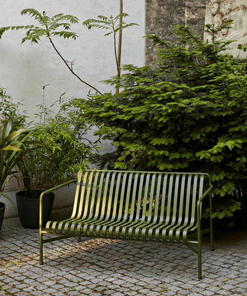 HAY Palissade Dining Bench in olive green next to green planting