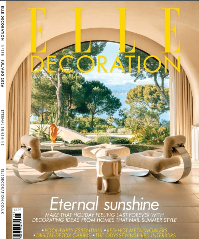 ELLE Decoration magazine cover featuring a sunlit Mediterranean-style interior with sculptural lounge chairs, a curved archway, and a lush garden view overlooking the sea.