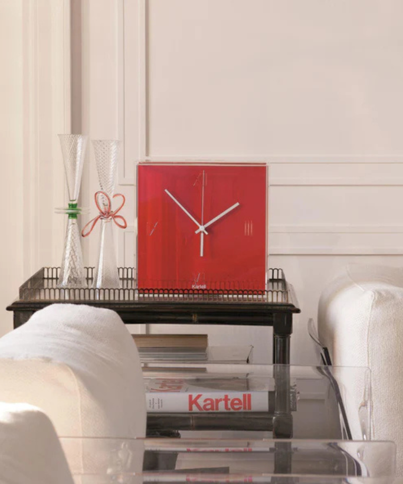 Red Kartell Tic&Tac wall clock set on a black side table