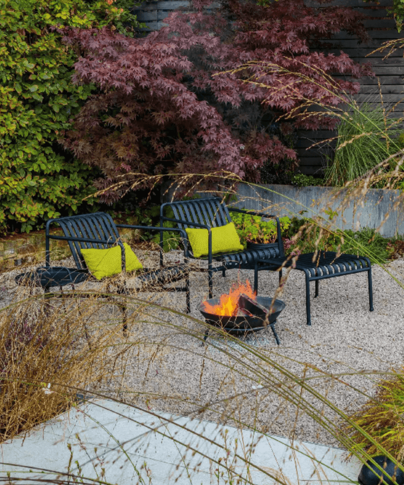 Contemporary garden design by Lucy Willcox with autumnal planting, Anthracite HAY Palissade Garden Lounge Furniture set around a black firepit with flame